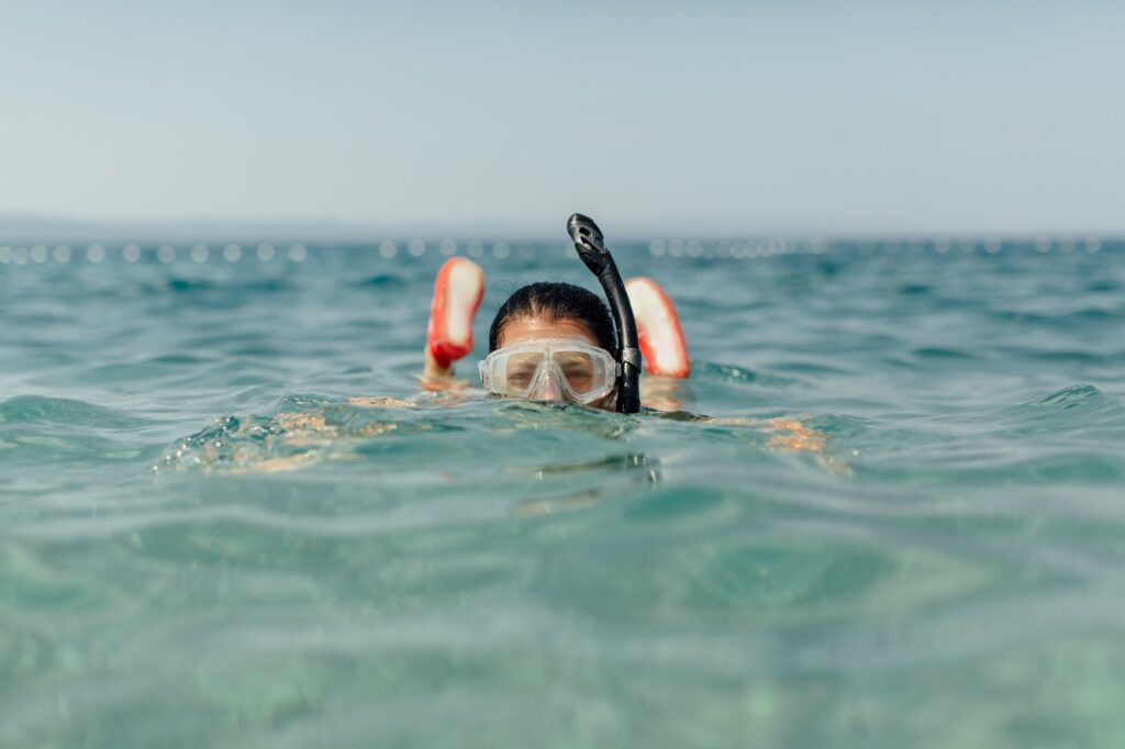 Woman wearing diving mask and snorkel swimming in sea.